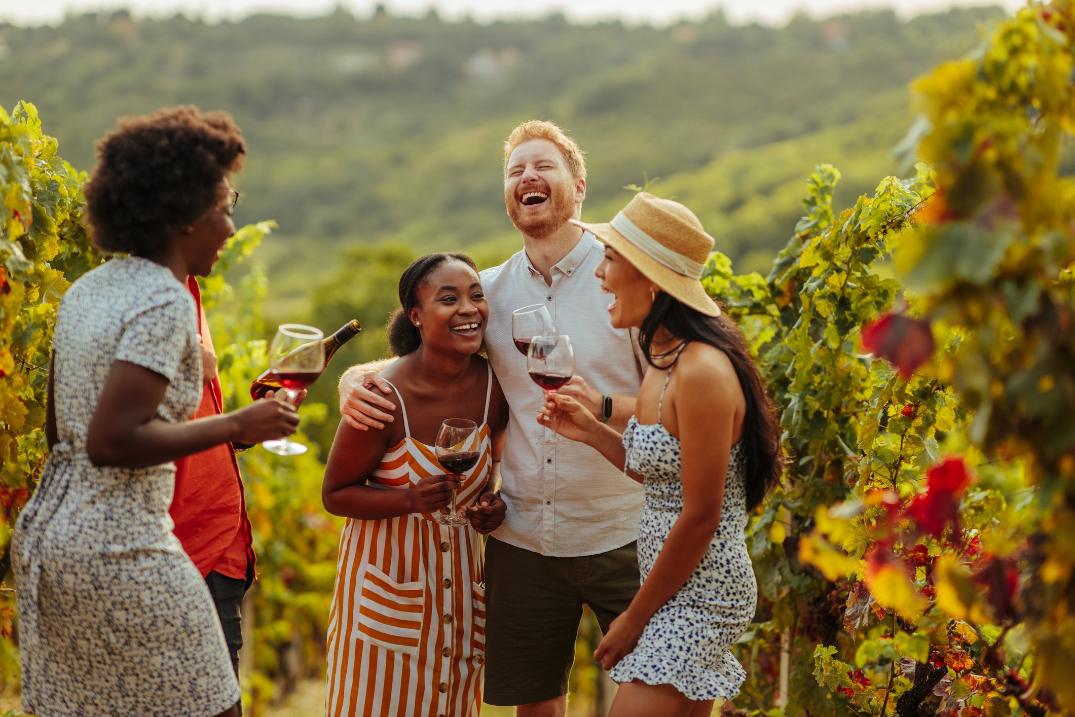 Grupo de quatro amigos felizes em uma vinícola com taças de vinho.