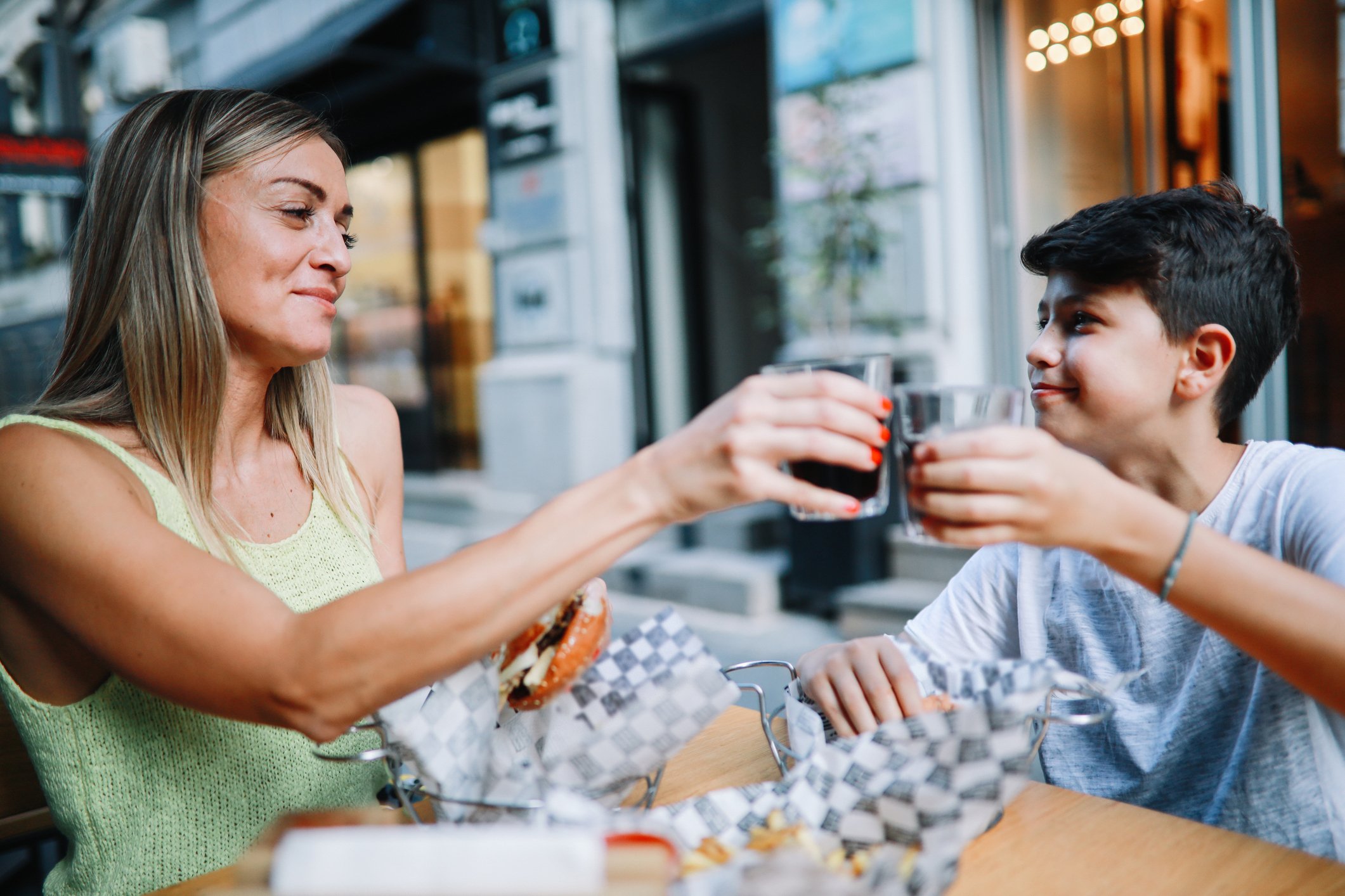 Mãe e filho fazendo um brinde em restaurante ao ar livre