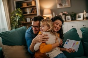 Família feliz se abraçando no sofá verde