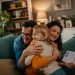 Família feliz se abraçando no sofá verde