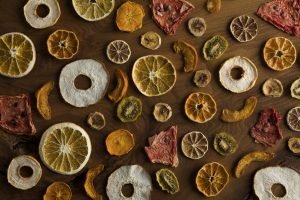 Fatias de frutas desidratadas organizadas sobre uma mesa de madeira.