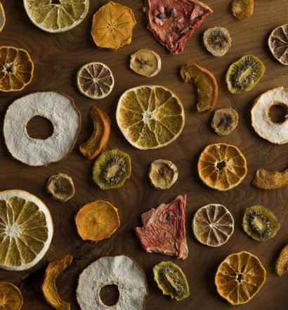 Fatias de frutas desidratadas organizadas sobre uma mesa de madeira.