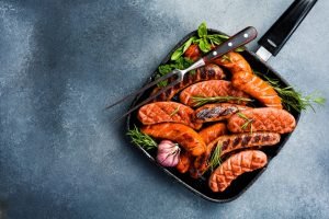 Linguiças grelhadas em uma frigideira com ervas.