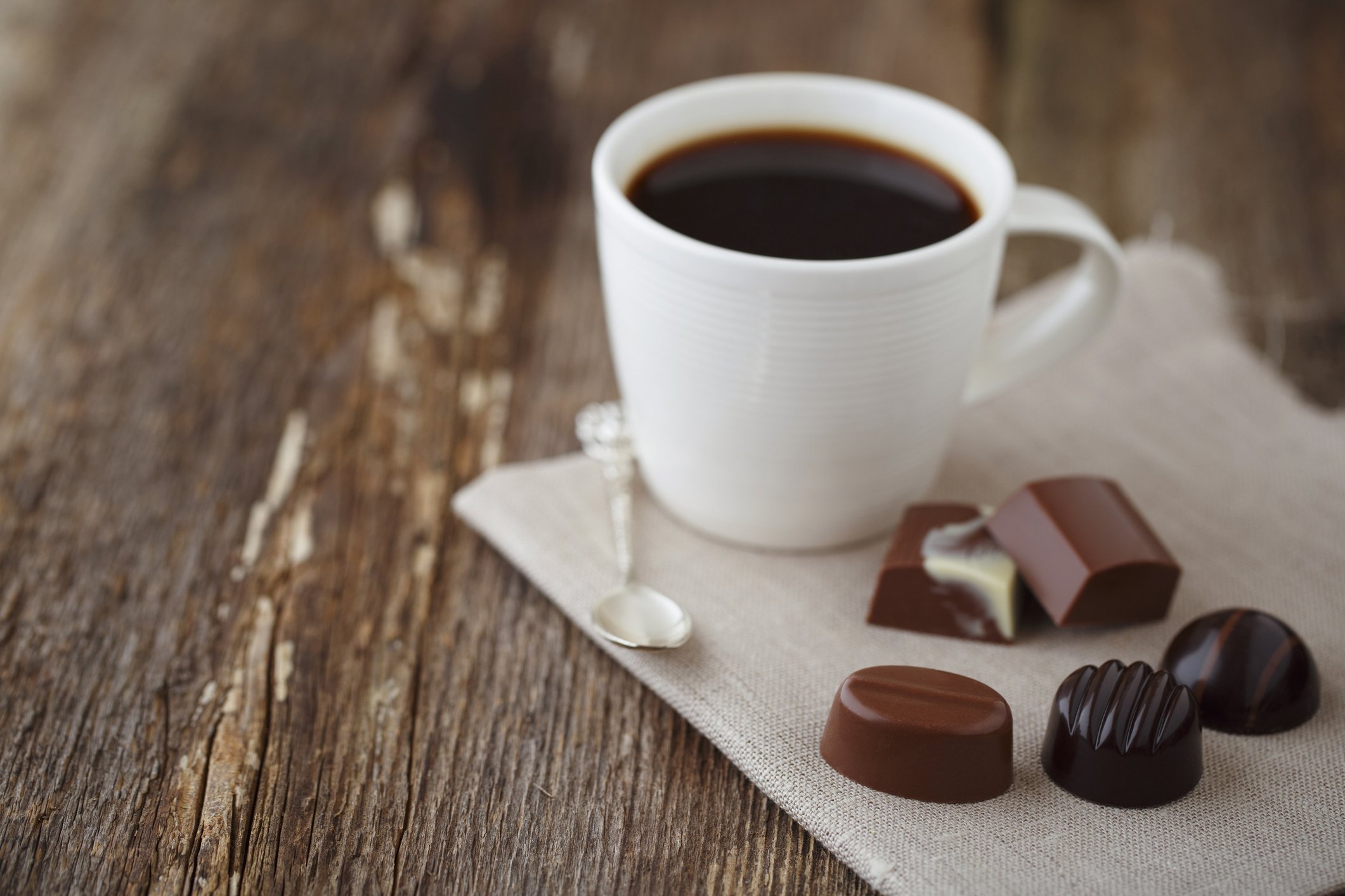 xícara de café branca com chocolates ao lado