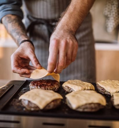 Queijo derretendo sobre hambúrguer na grelha