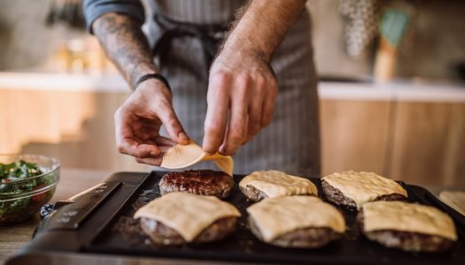 Queijo derretendo sobre hambúrguer na grelha