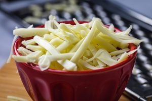Queijo Monterey Jack ralado em tigela vermelha, ideal para hambúrguer