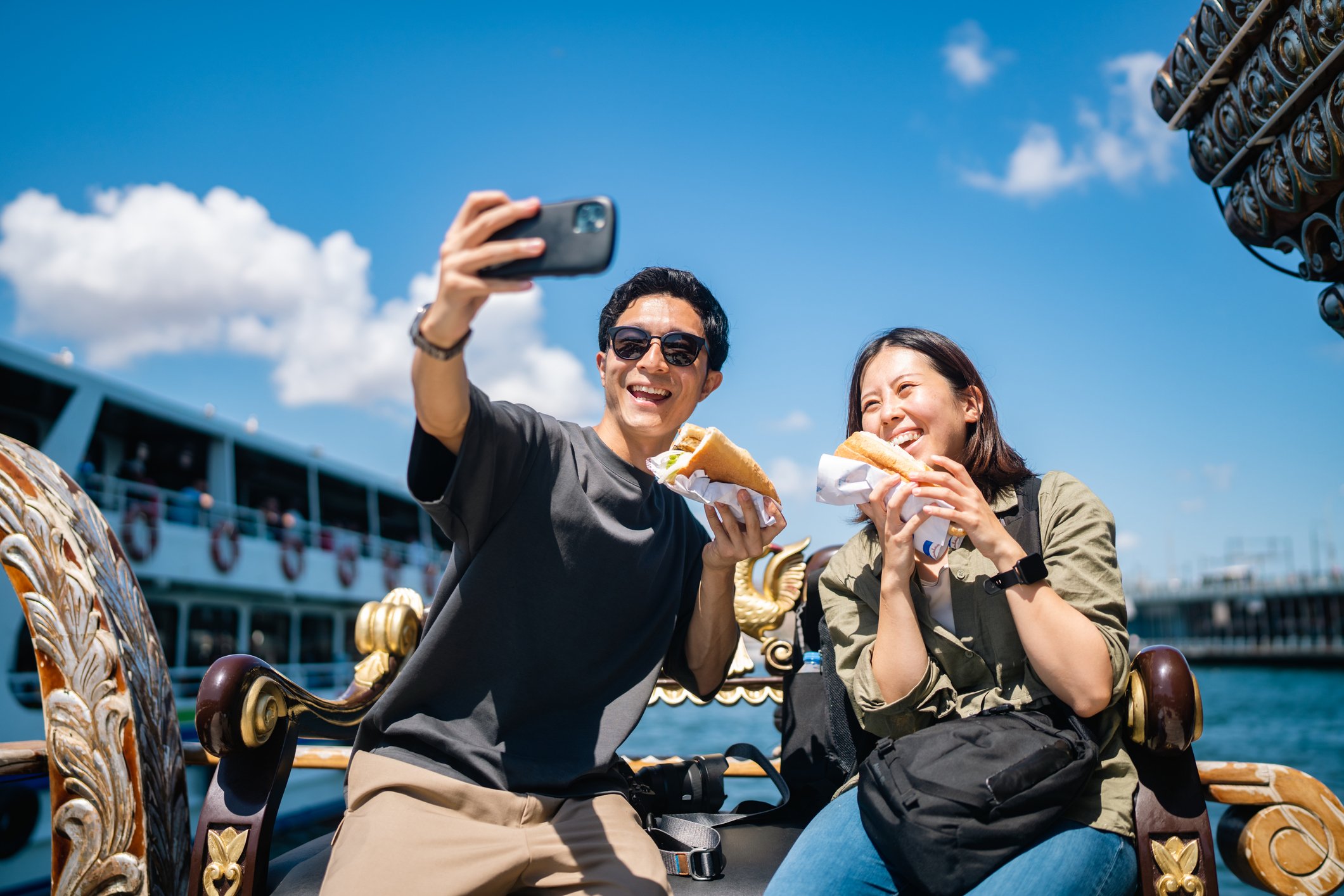 Casal sorridente tirando selfie com comida em um passeio.