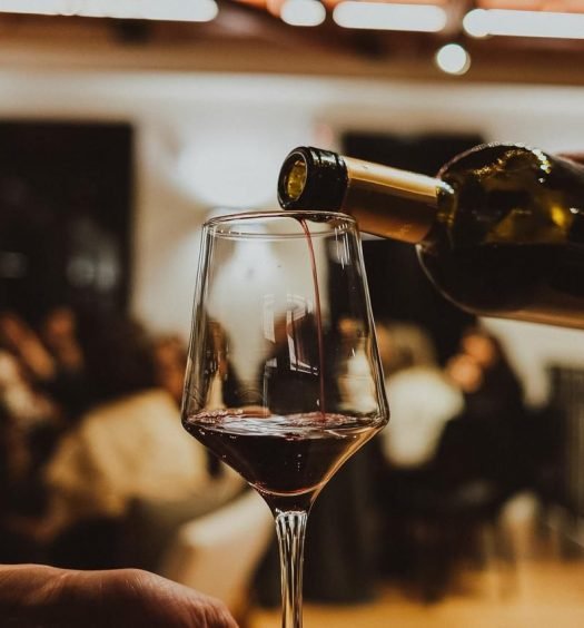 Taça sendo servida com vinho tinto durante a Experiência Cliente Mais Black em vinhedos gauchos