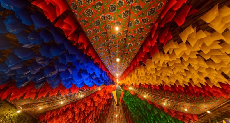 Decoração colorida de Festa Junina com bandeirinhas e lanternas.