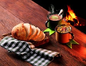 Pão de milho e caldos servidos em uma mesa rústica durante a Festa Junina.