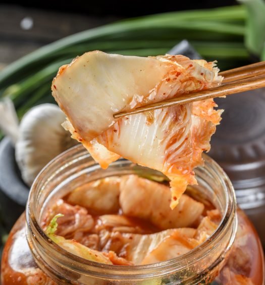 Kimchi sendo retirado de um pote com hashi