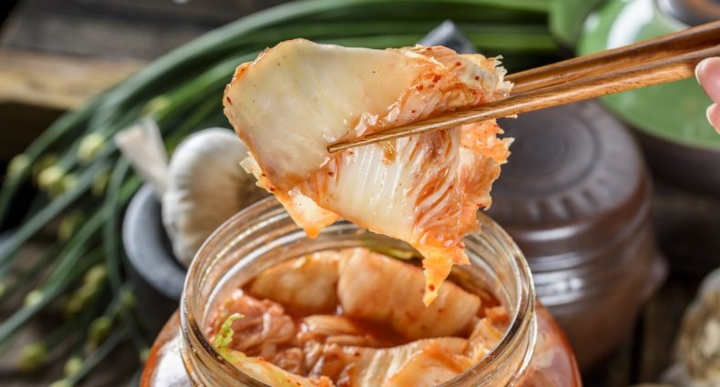 Kimchi sendo retirado de um pote com hashi