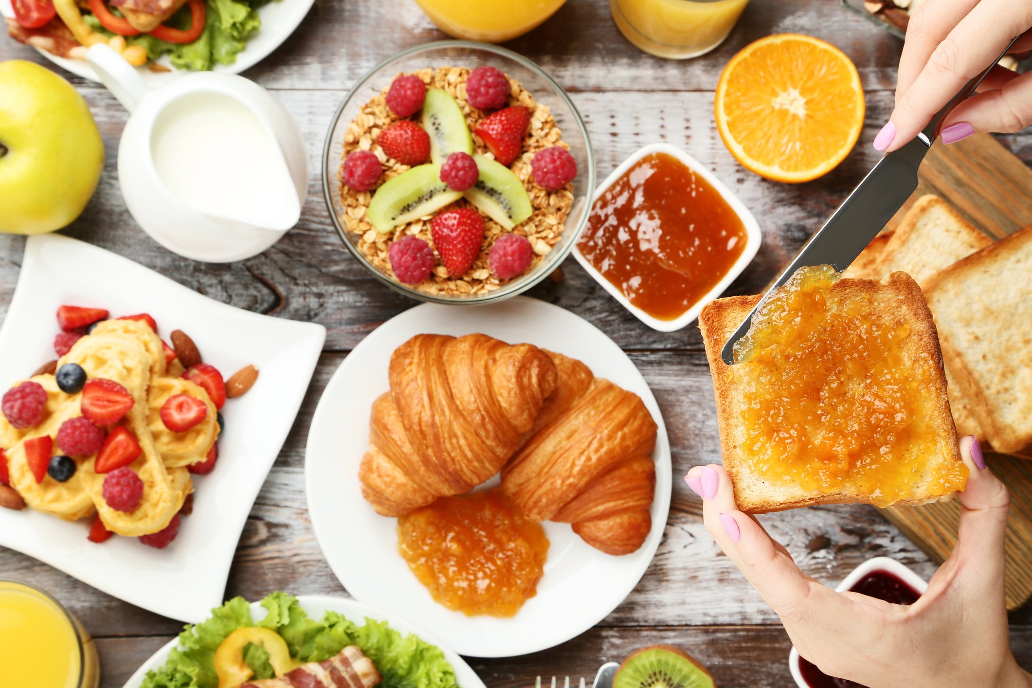Mesa repleta de alimentos frescos e geleia, ideal para o café da manhã.