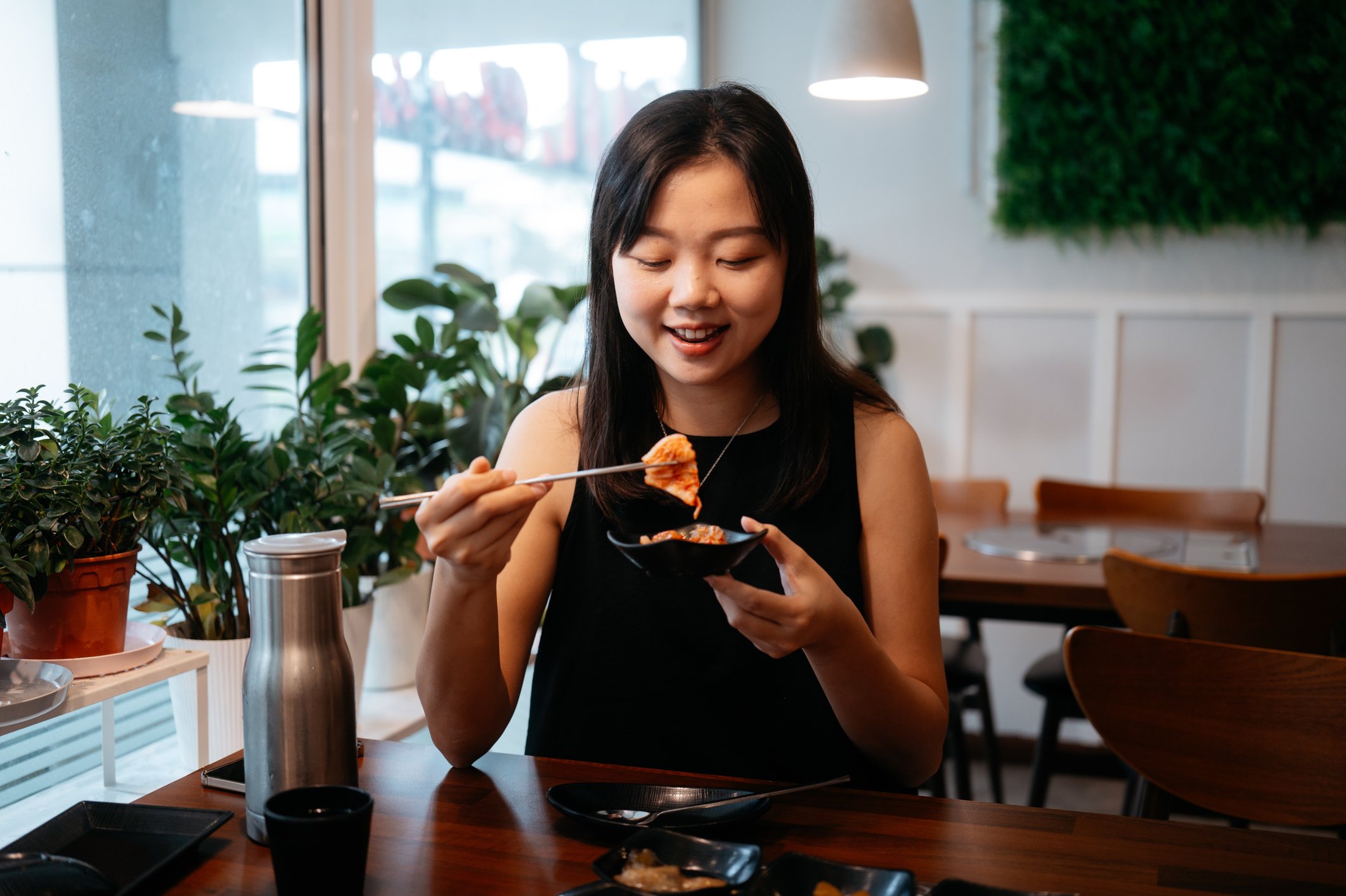 Mulher comendo kimchi em um restaurante