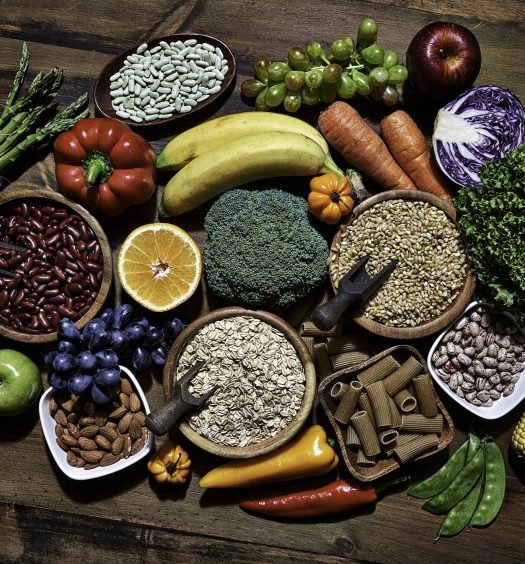 Variados alimentos ricos em fibras, incluindo frutas, verduras e grãos.
