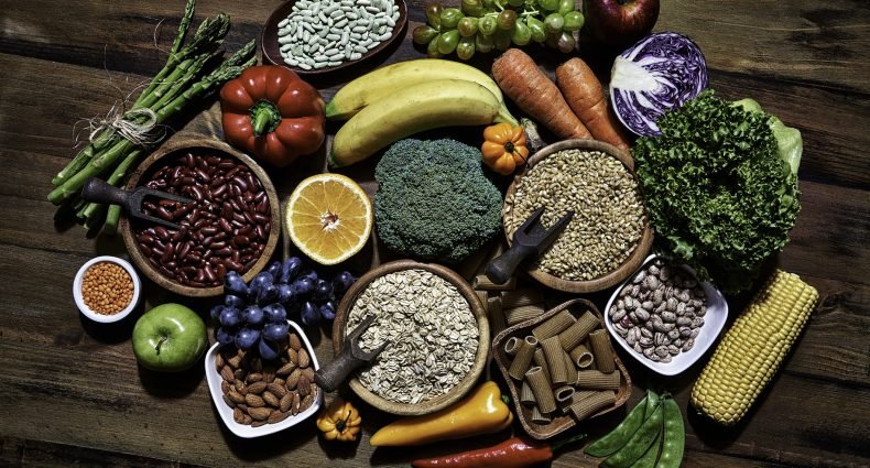 Variados alimentos ricos em fibras, incluindo frutas, verduras e grãos.