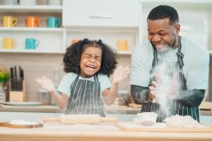 Pai e filha se divertindo enquanto cozinham juntos.