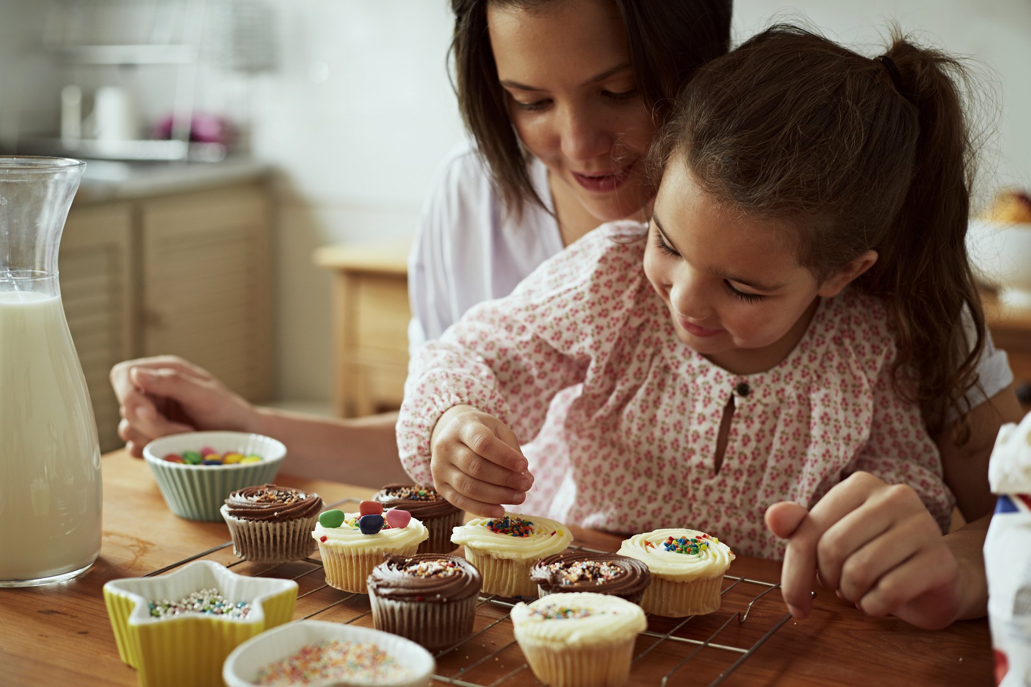 Mãe e filha decorando cupcakes divertidos na cozinha