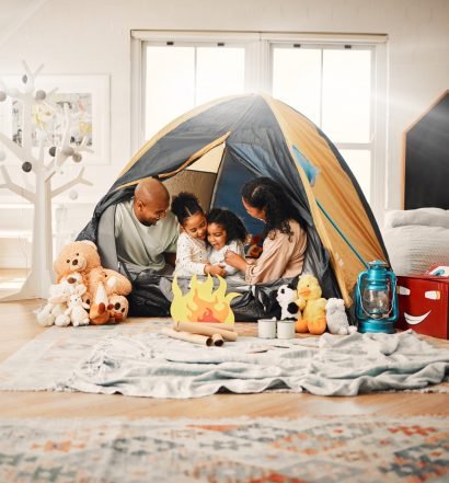 Família desfrutando de férias em casa, com crianças brincando em uma barraca.