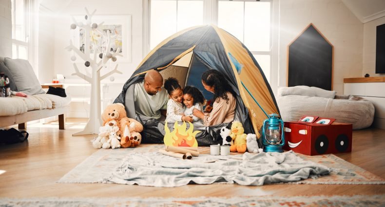 Família desfrutando de férias em casa, com crianças brincando em uma barraca.