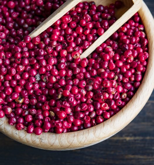 Grãos de pimenta rosa em uma tigela de madeira.