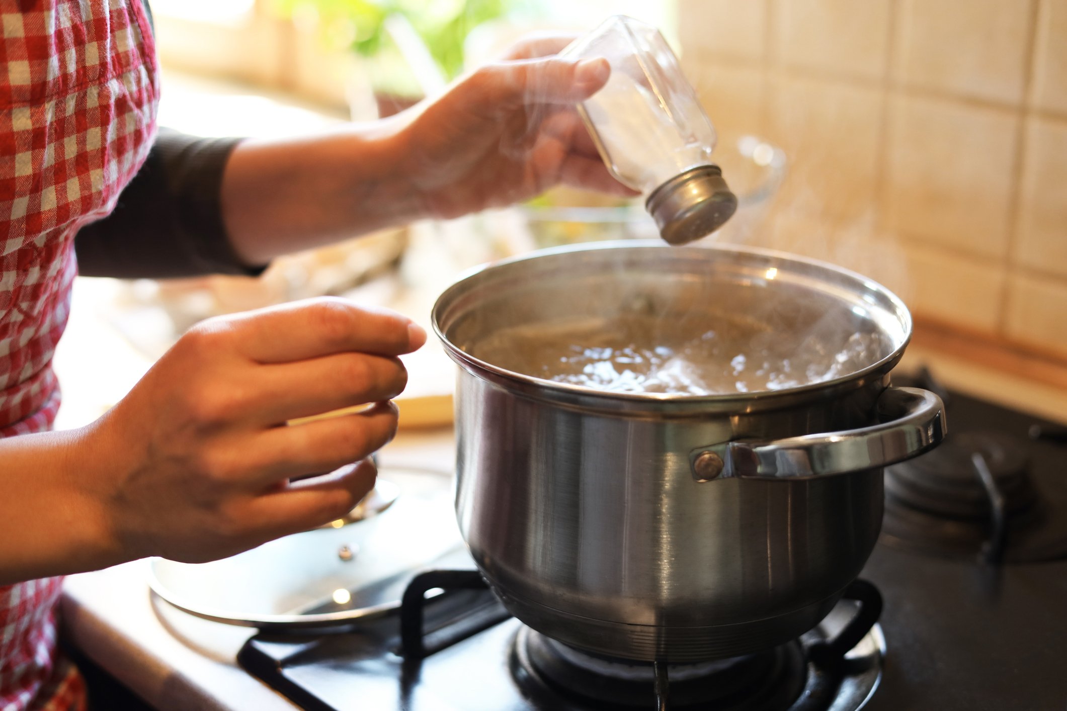Mão adicionando sal a uma panela de feijoada