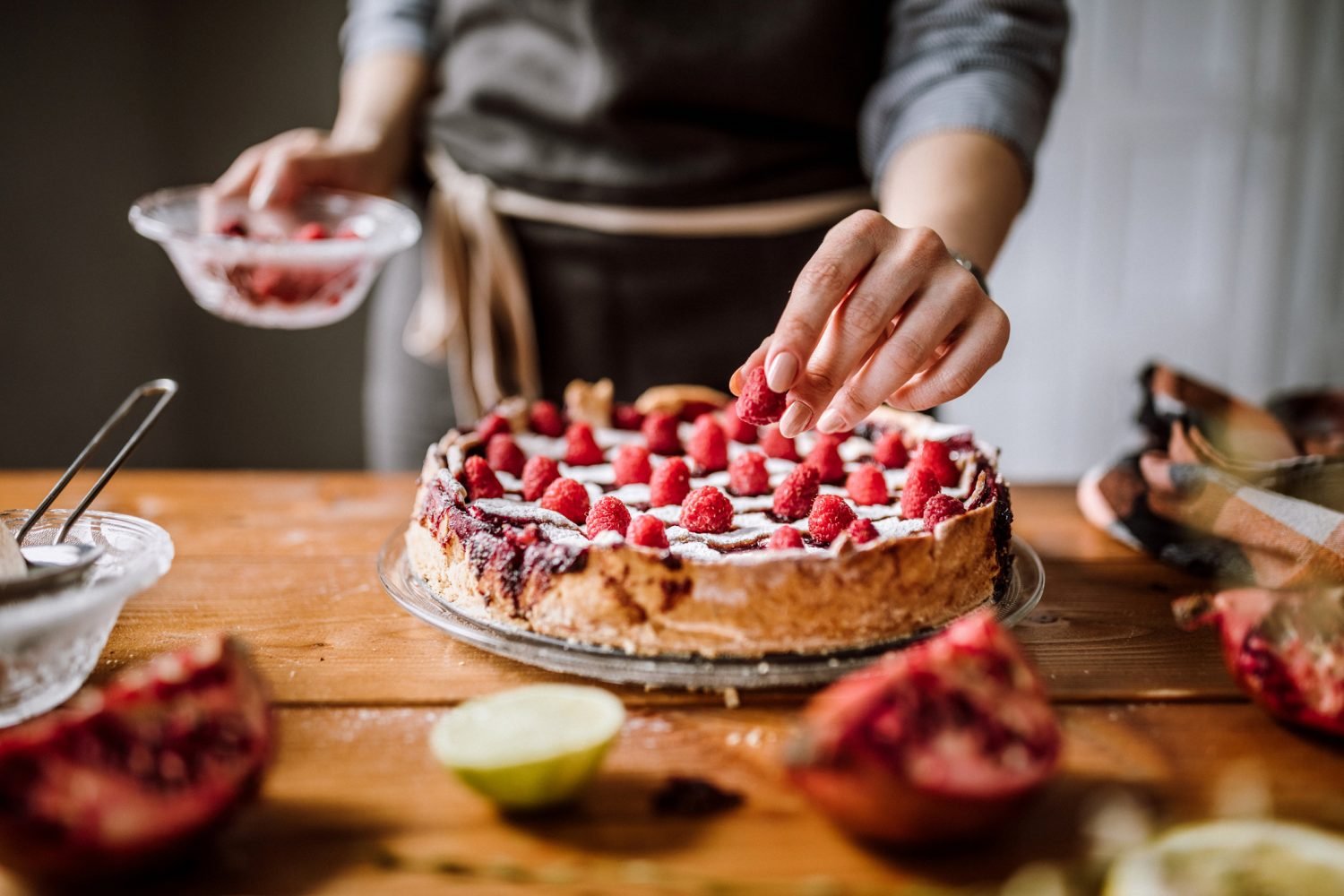 Mulher adicionando frutas em torta de morangos frescos.