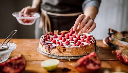 Mulher adicionando frutas em torta de morangos frescos.
