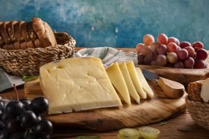 Acompanhamentos como pães e uvas que combinam com queijo gruyère para uma mesa refinada.