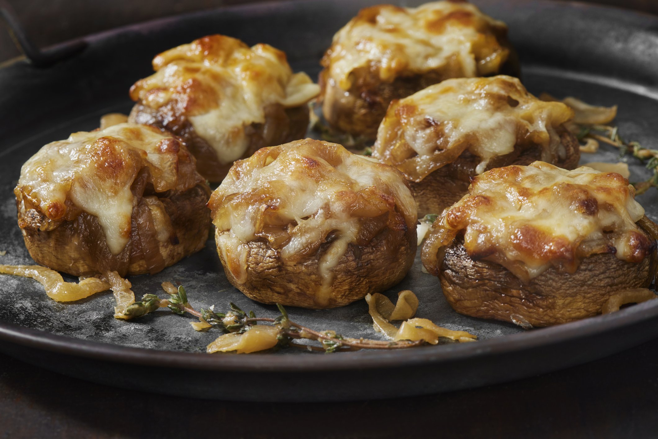 Queijo gruyère derretido sobre cogumelos recheados, um prato delicioso e sofisticado.