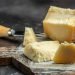 Queijo gruyère cortado em pedaços sobre uma tábua de madeira, mostrando sua textura e versatilidade para diferentes pratos.