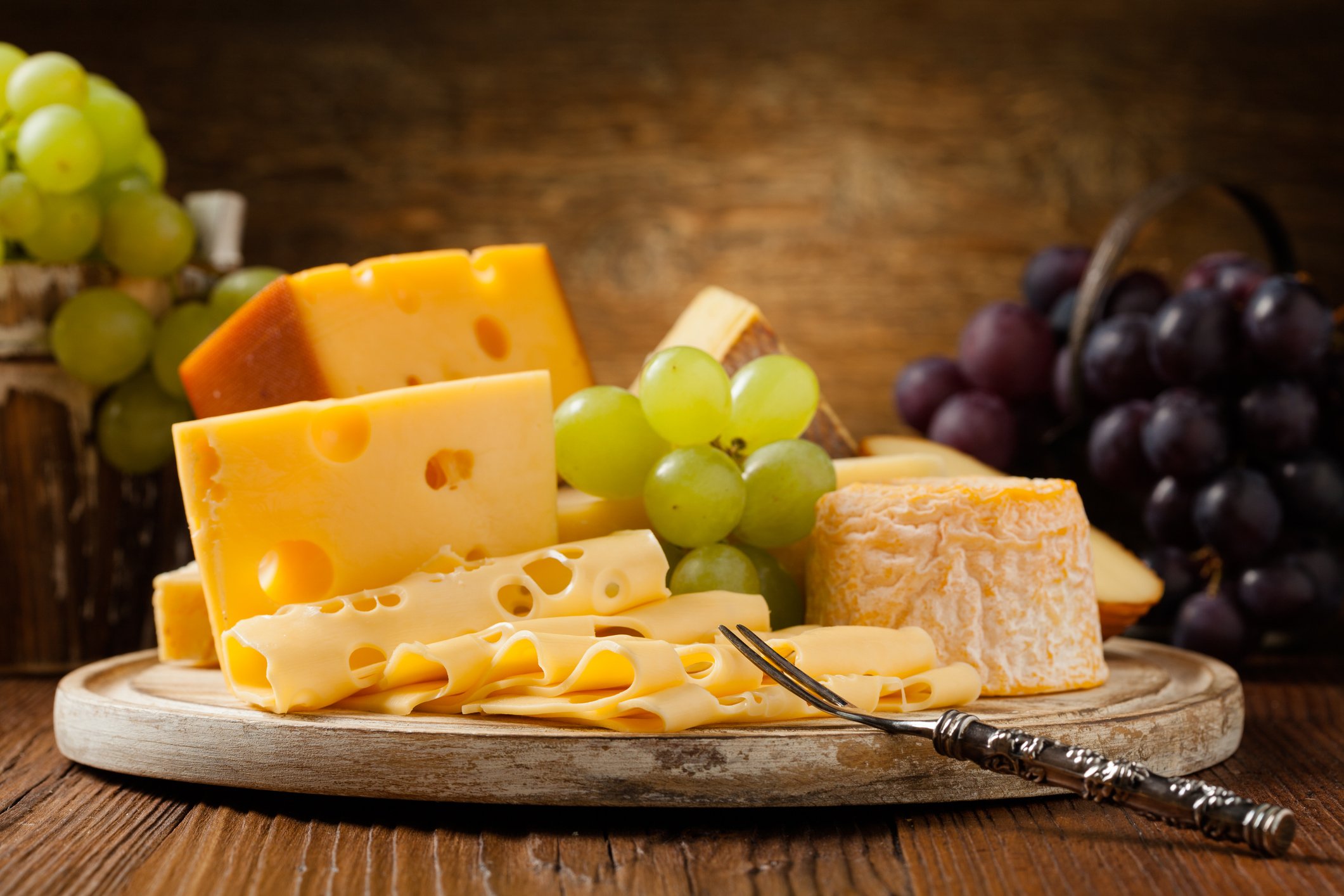 Diversos queijos complementando o sabor do gruyère, com uvas e elementos que realçam suas características.