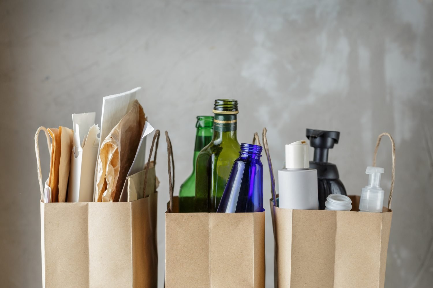 Sacos de papel contendo lixo reciclável, incluindo vidro e plásticos.