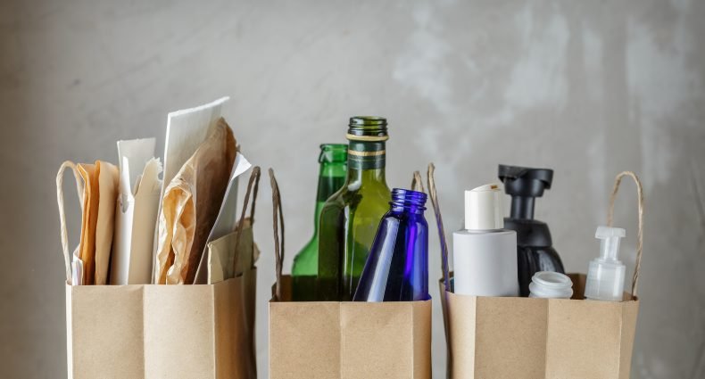 Sacos de papel contendo lixo reciclável, incluindo vidro e plásticos.