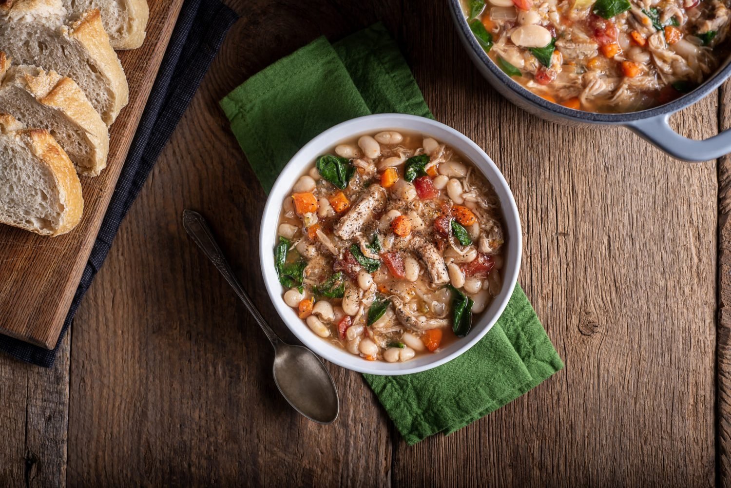 Sopa de feijão cremosa com legumes e um pedaço de pão.