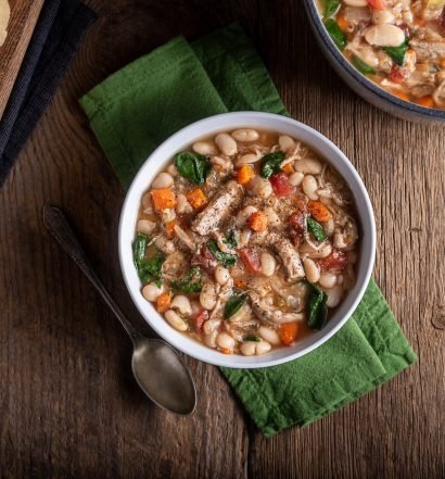 Sopa de feijão cremosa com legumes e um pedaço de pão.