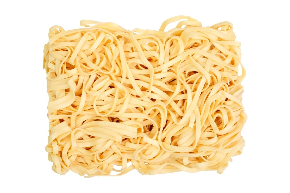 Um bloco de tagliatelle fresco sobre uma superfície clara.
