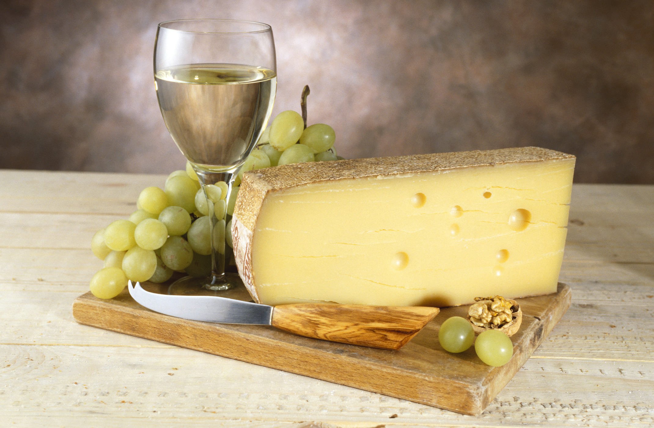 Queijo gruyère acompanhado de uma taça de vinho e uvas, representando combinações perfeitas para uma experiência gourmet.