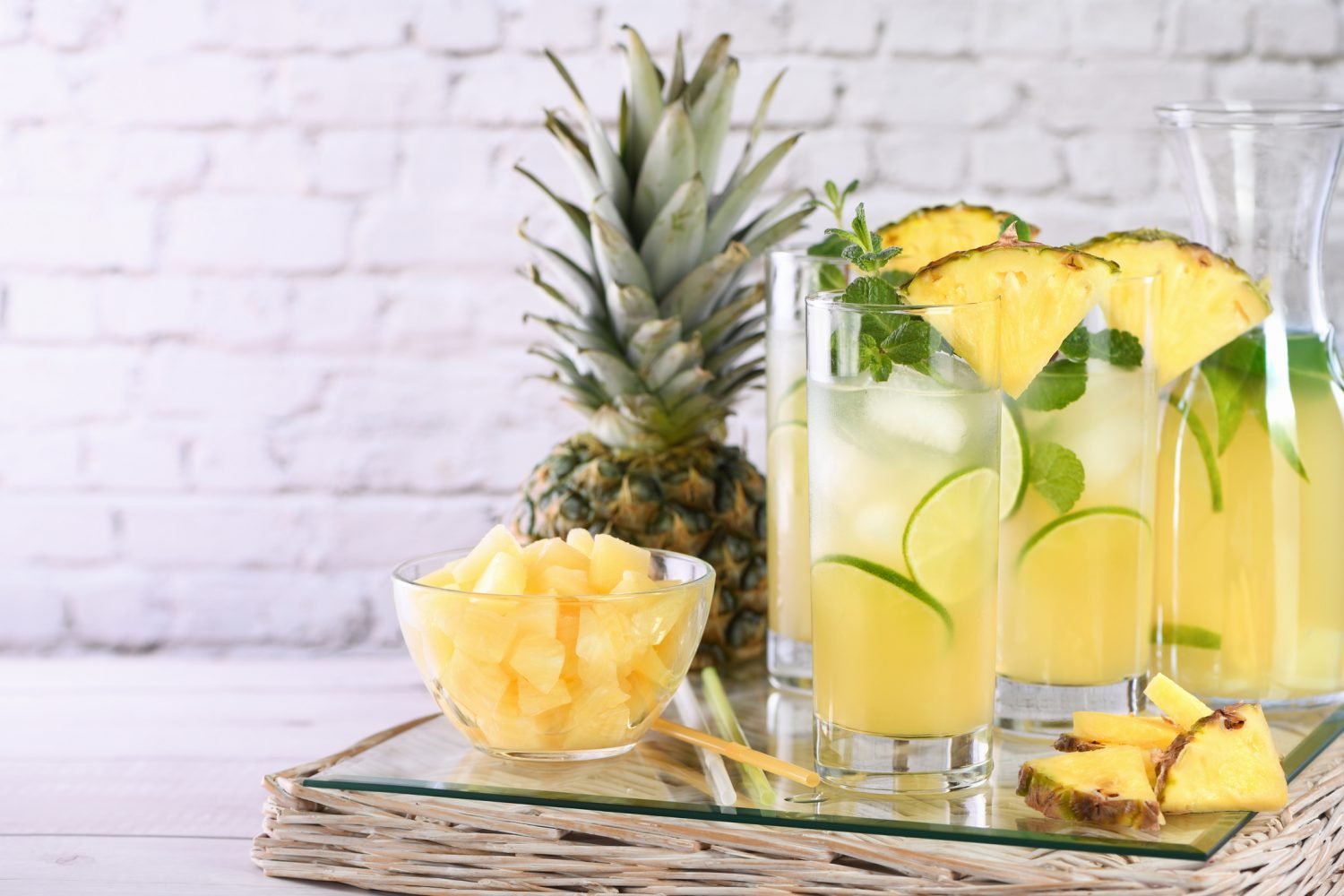 Caipirinha de abacaxi com fatias e cubos de abacaxi em copos altos