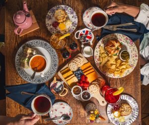 Mesa completa de chá da tarde com bolos, queijos e frutas