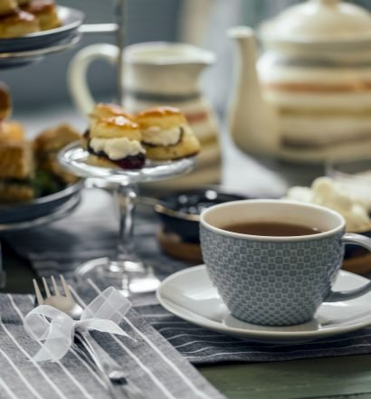 Xícara de chá elegante com petiscos em mesa posta para chá da tarde