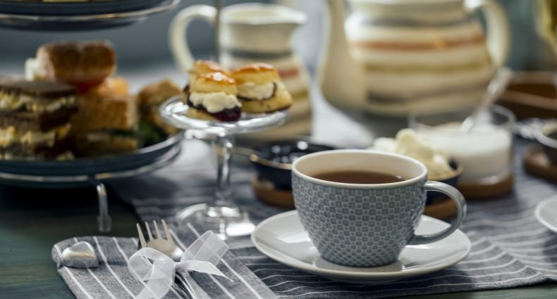 Xícara de chá elegante com petiscos em mesa posta para chá da tarde