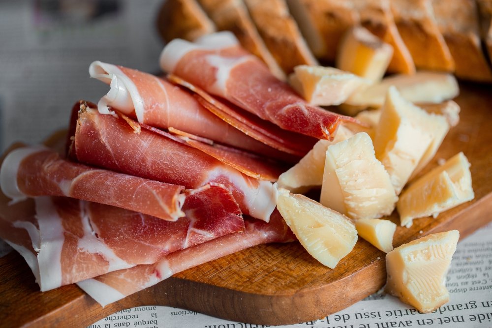 Presunto parma servido com pedaços de queijo e pão artesanal