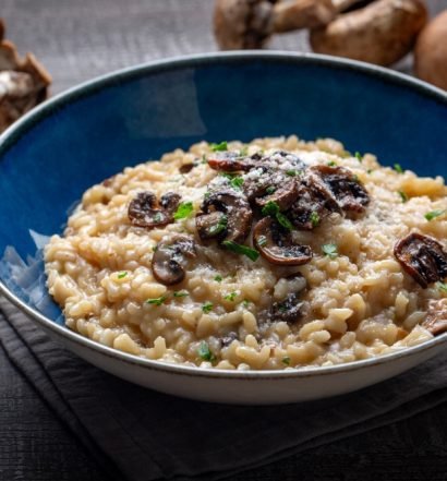 Risoto de funghi cremoso servido em tigela azul com cogumelos salteados por cima