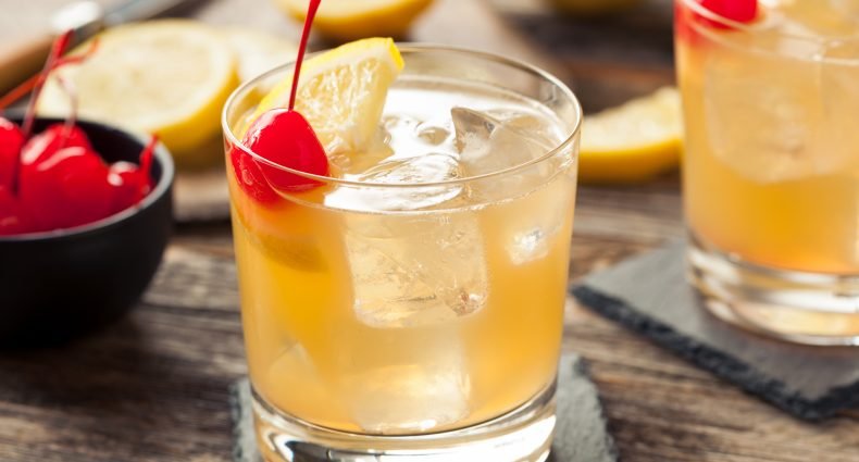 Variação colorida de Whisky Sour em um copo decorado.