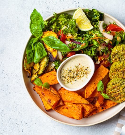 Prato vegano com falafel, batata-doce, salada verde e molho tahine para celebrar o Dia Mundial do Veganismo