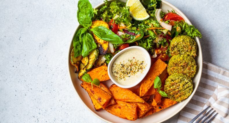 Prato vegano com falafel, batata-doce, salada verde e molho tahine para celebrar o Dia Mundial do Veganismo