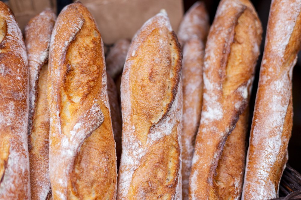 Baguetes francesas artesanais com farinha polvilhada dispostas em cesta para o Dia Mundial do Pão