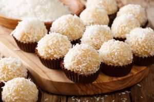 Beijinhos de coco gourmet em forminhas de chocolate, cobertos com coco ralado, perfeitos para festas infantis ou uma sobremesa fácil de fazer com crianças.